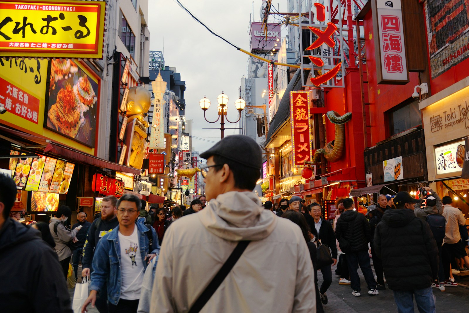 A group of people walking down a street next to tall buildings